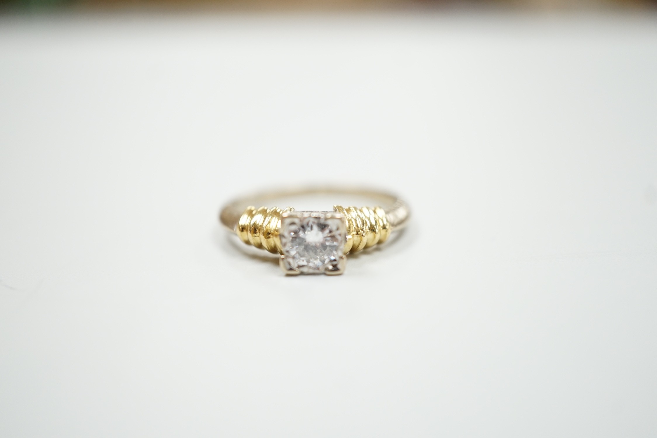 A modern 18ct two colour gold and solitaire diamond set ring, size H/I, gross weight 3.3 grams.